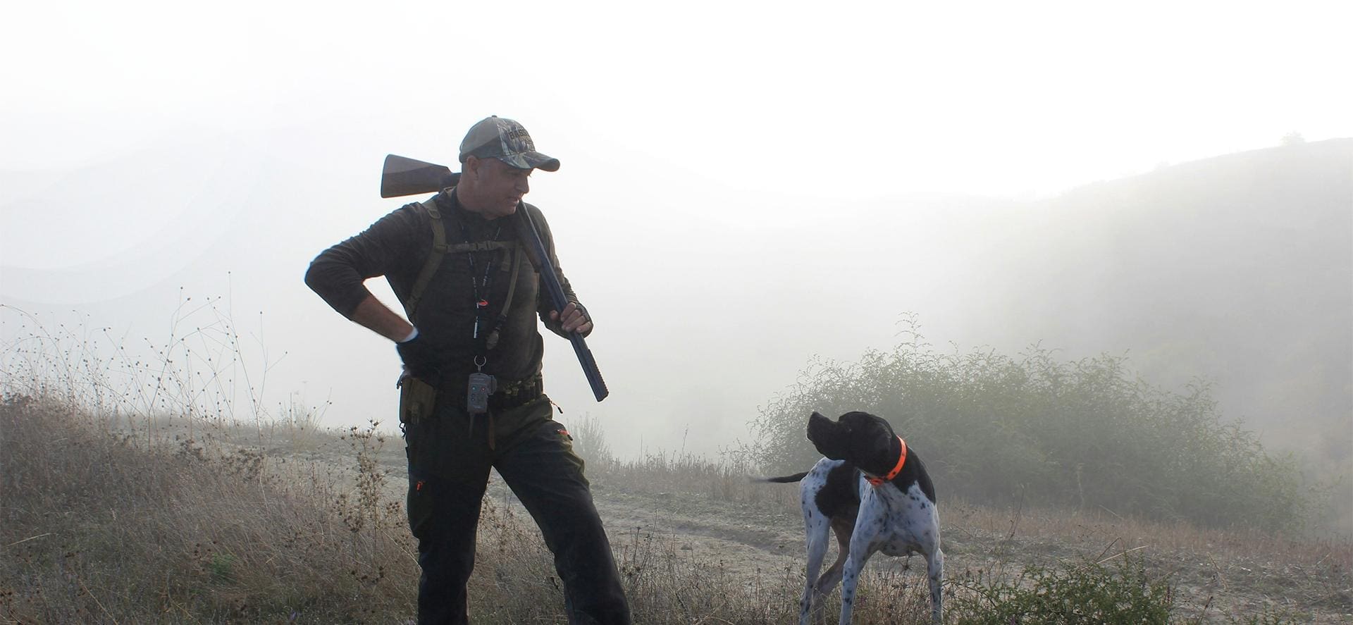 A man and his dog are hunting in the fog.